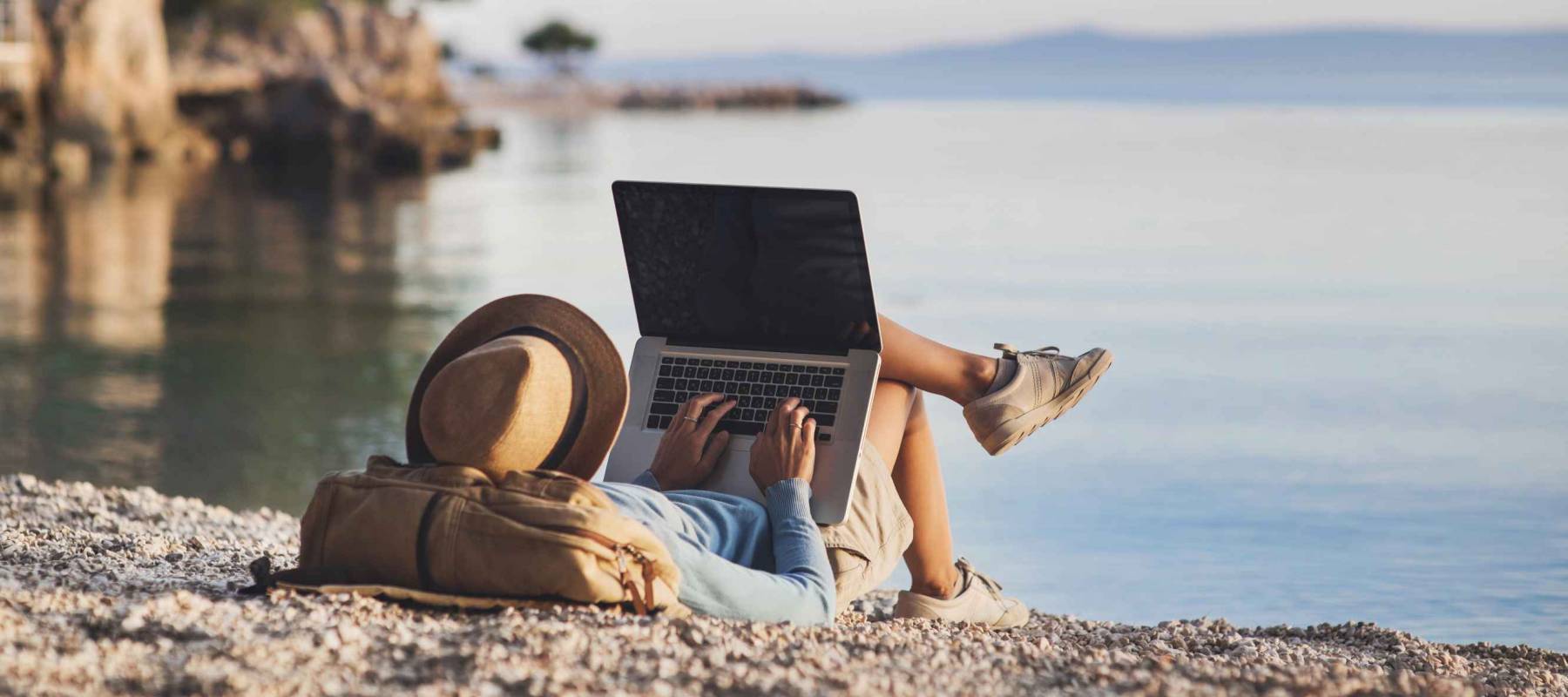 Young woman using laptop computer on a beach. Freelance work concept
