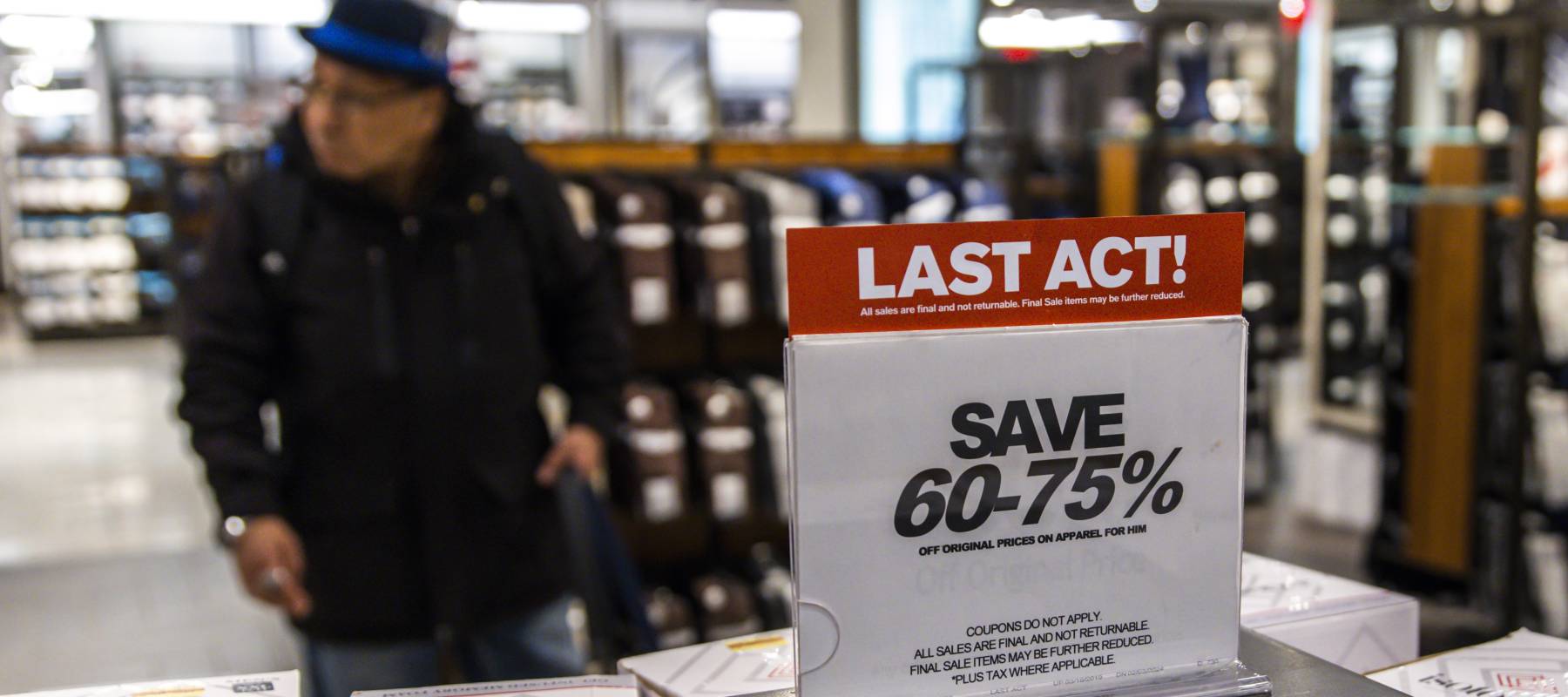 Man in a Macy's store, behind a Last Act sale sign.