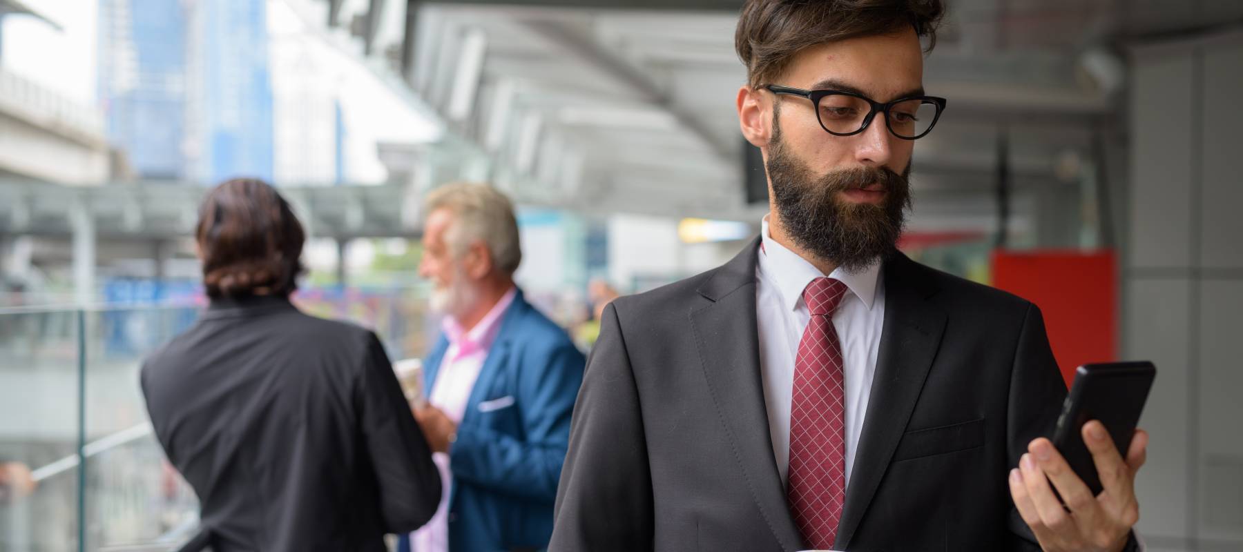 A man dressed in a suit looks at his phone.