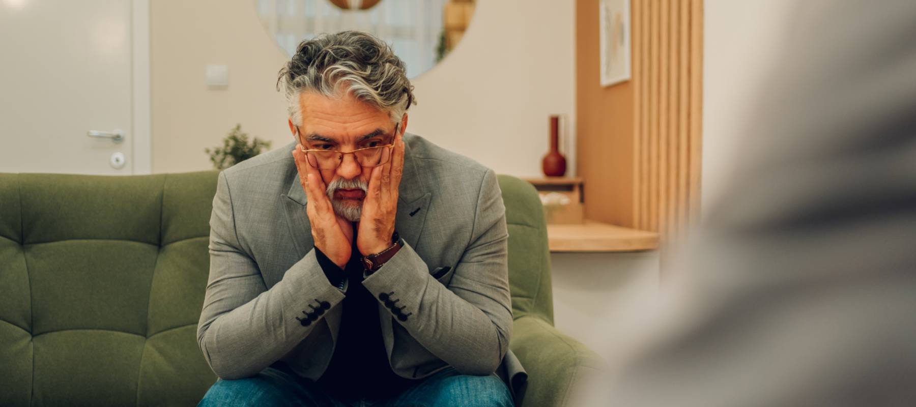 A worried and anxious senior man is sitting in a psychotherapist's office.
