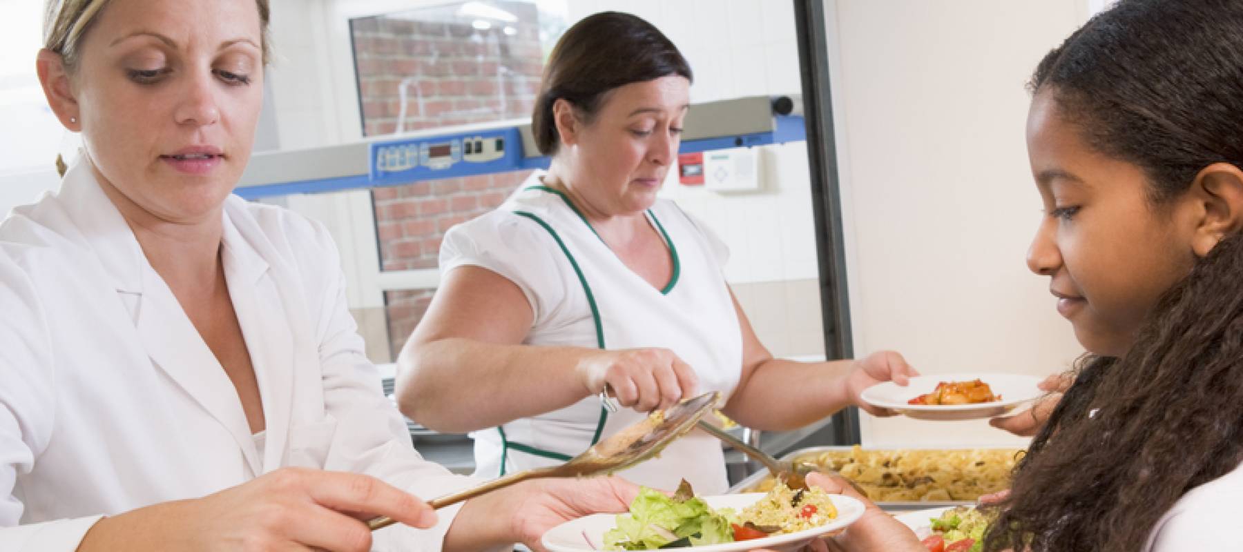 Cafeteria staff feed student.