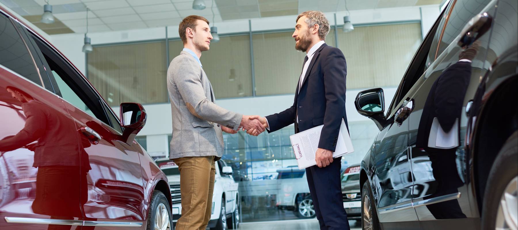 Two men shaking hands in car dealership