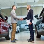 Two men shaking hands in car dealership