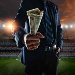 businessman holding large amount of bills at stadium