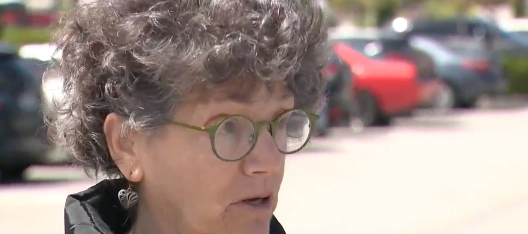 Woman talking on camera in a parking lot.