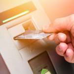 Hand of a man with a credit card, using an ATM. Man using an atm machine with his credit card.