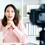 Young asian woman vlogger looking at camera and talking on video