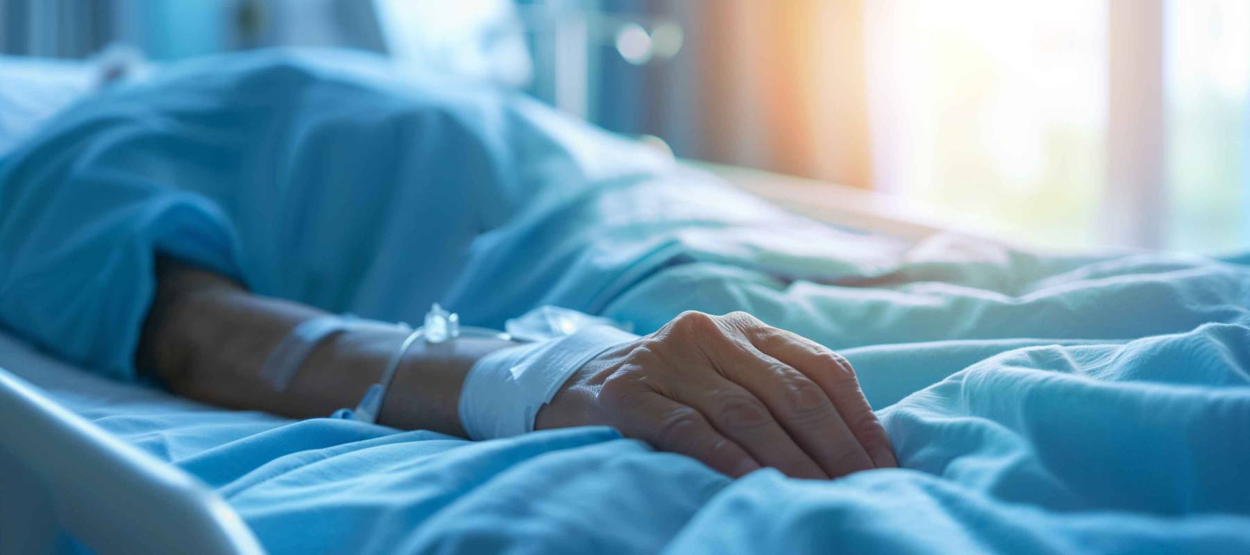 Closeup of patient's arm with IV drip in a hospital bed
