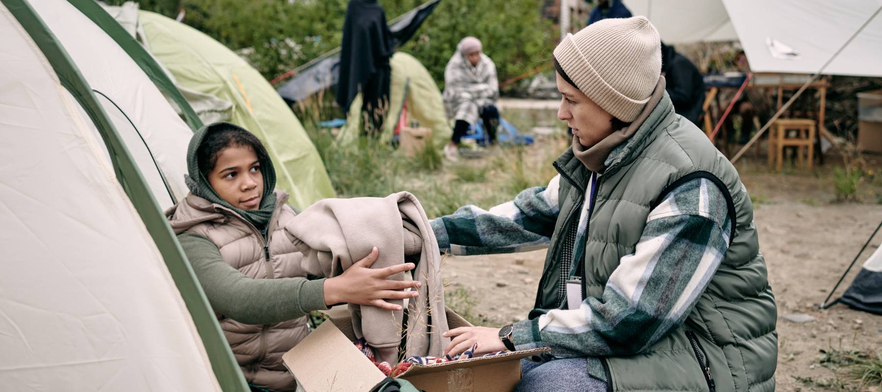 Woman handing woman blanket in a tent