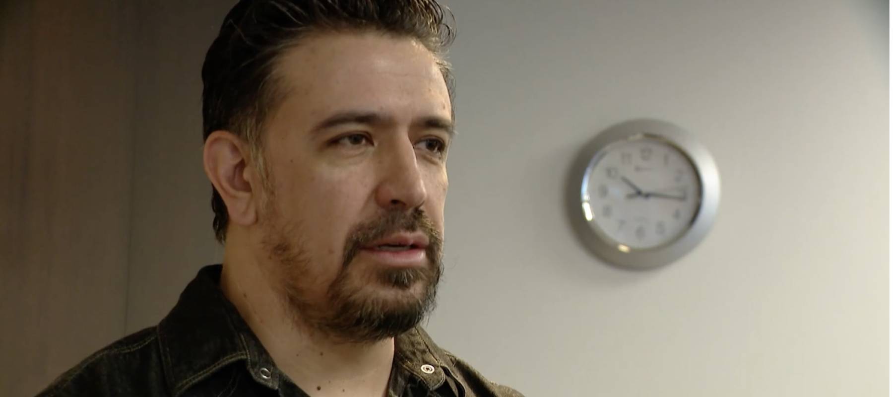 Man speaks to the camera, looking to the side with unhappy expression.