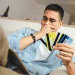 Man holding four credit cards looking at his computer