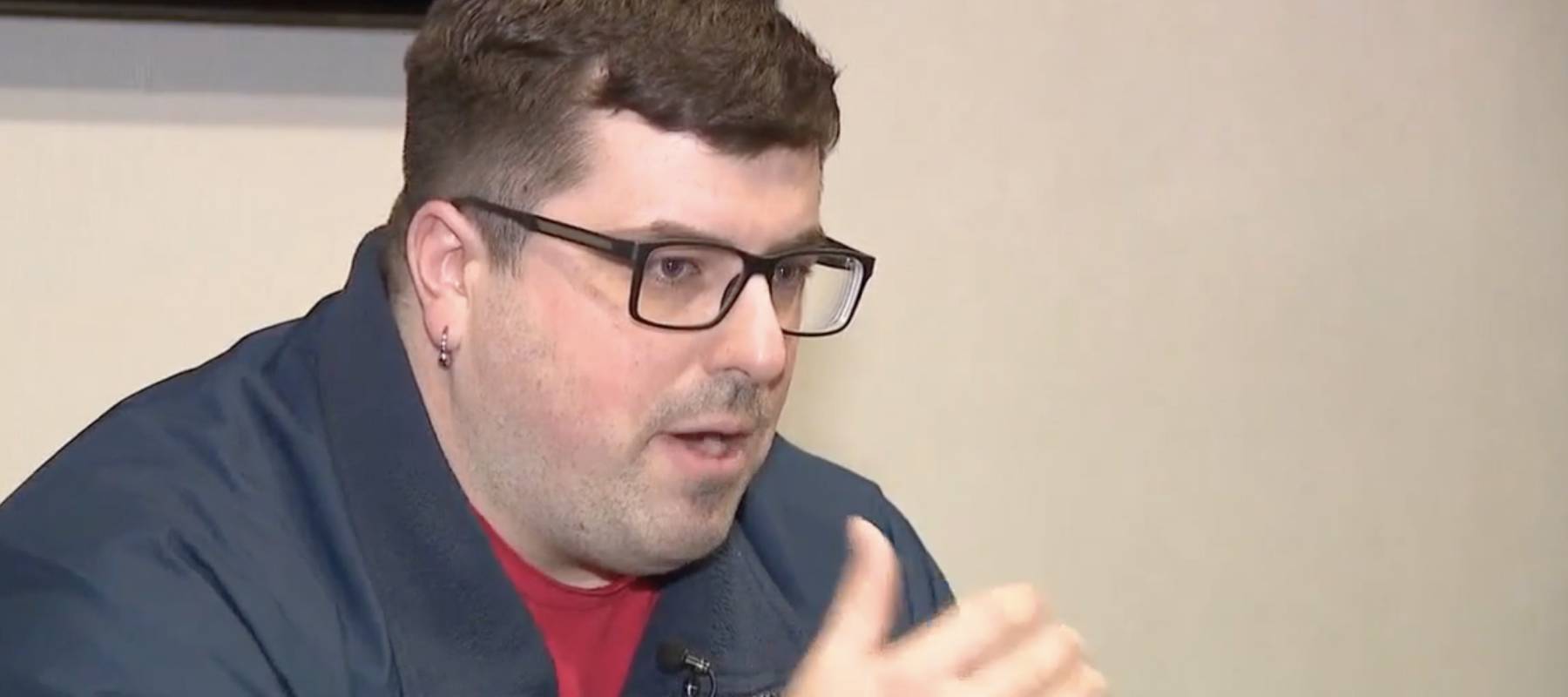 Man looks down, speaking to reporter on camera.