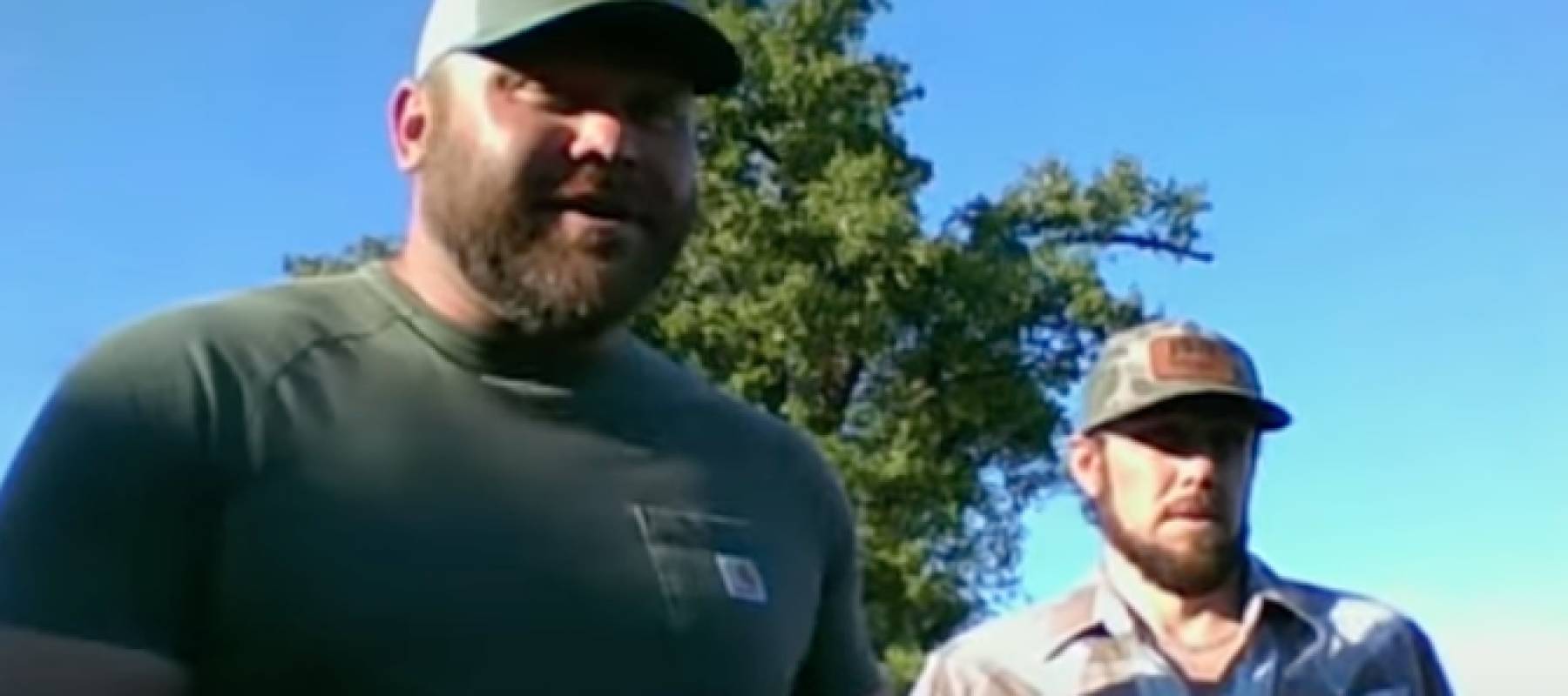 Two brothers speak on camera in front of a tree.