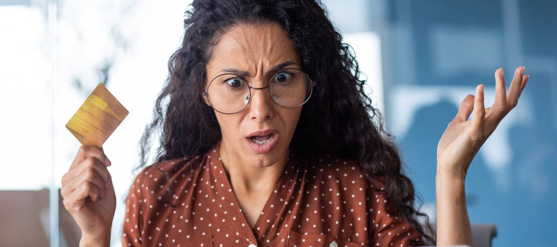Upset and shocked business woman with bank credit card and laptop