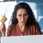 Upset and shocked business woman with bank credit card and laptop