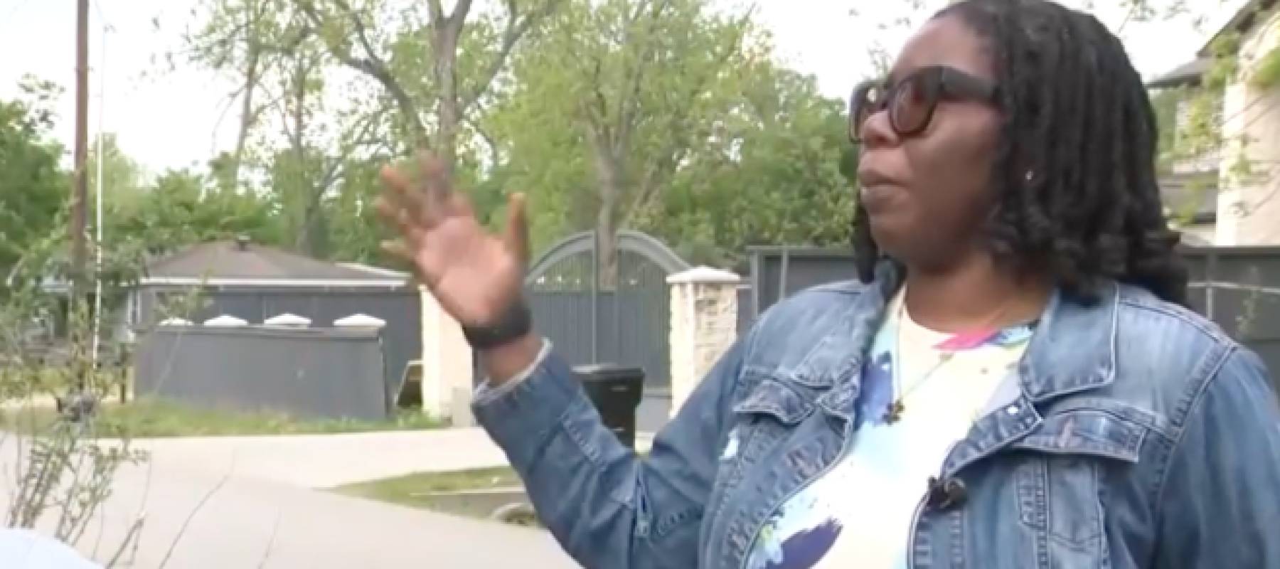 Woman motions to house off screen.