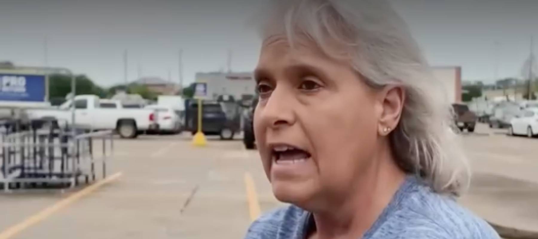 Woman speaks to reporter in a parking lot.