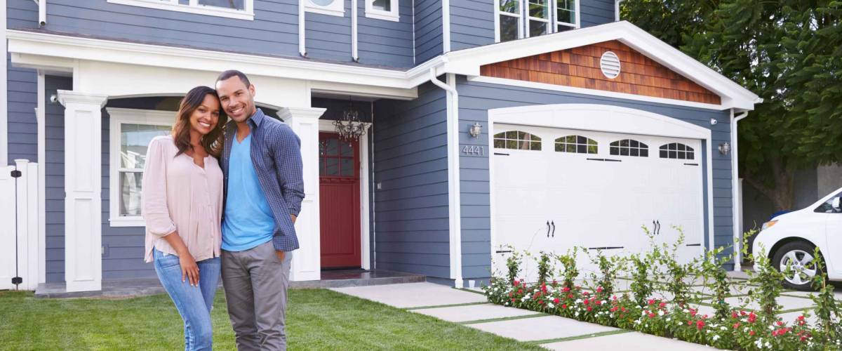Happy black couple standing outside their house