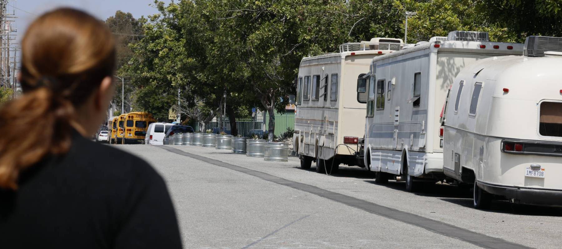 Woman standing across the street from RVs that house homeless people in LA.
