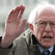 Bernie Sanders speaks on Capitol Hill with a serious look on his face and his hand held up.