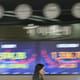 A currency trader walks by the screens showing the Korea Composite Stock Price Index (KOSPI), left, and the foreign exchange rate between U.S. dollar and South Korean won at a foreign exchang