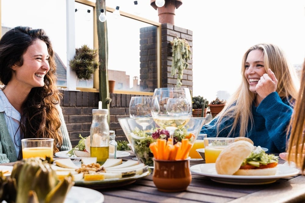two young women laughing on at an outdoor patio