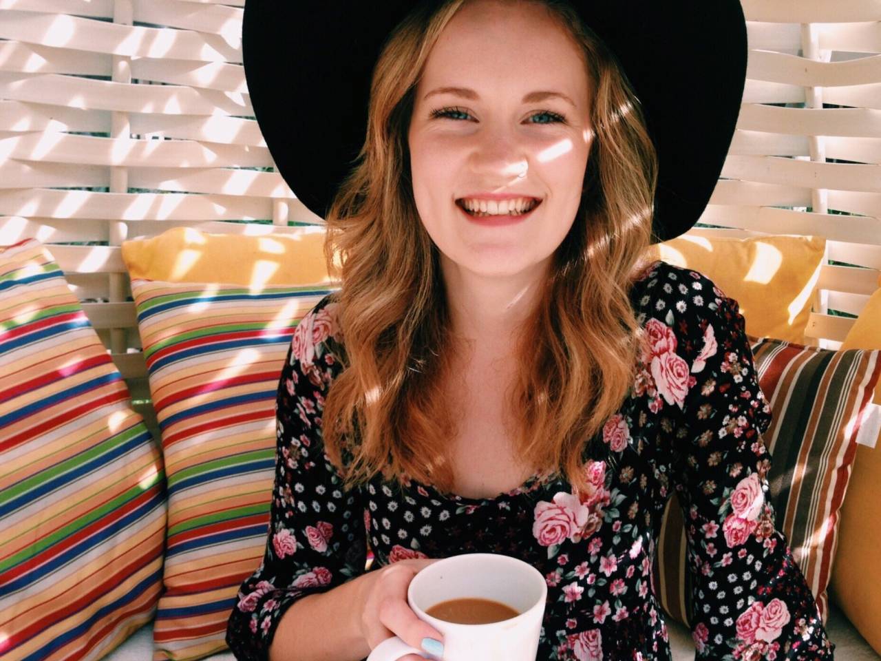 Young woman smiling and holding coffee.