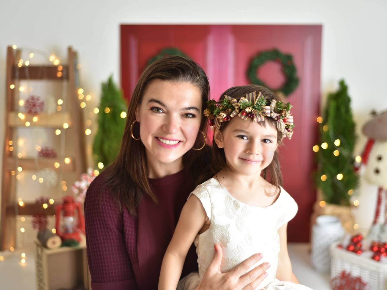 Smiling mother and young daughter surrounded by Christmas decorations