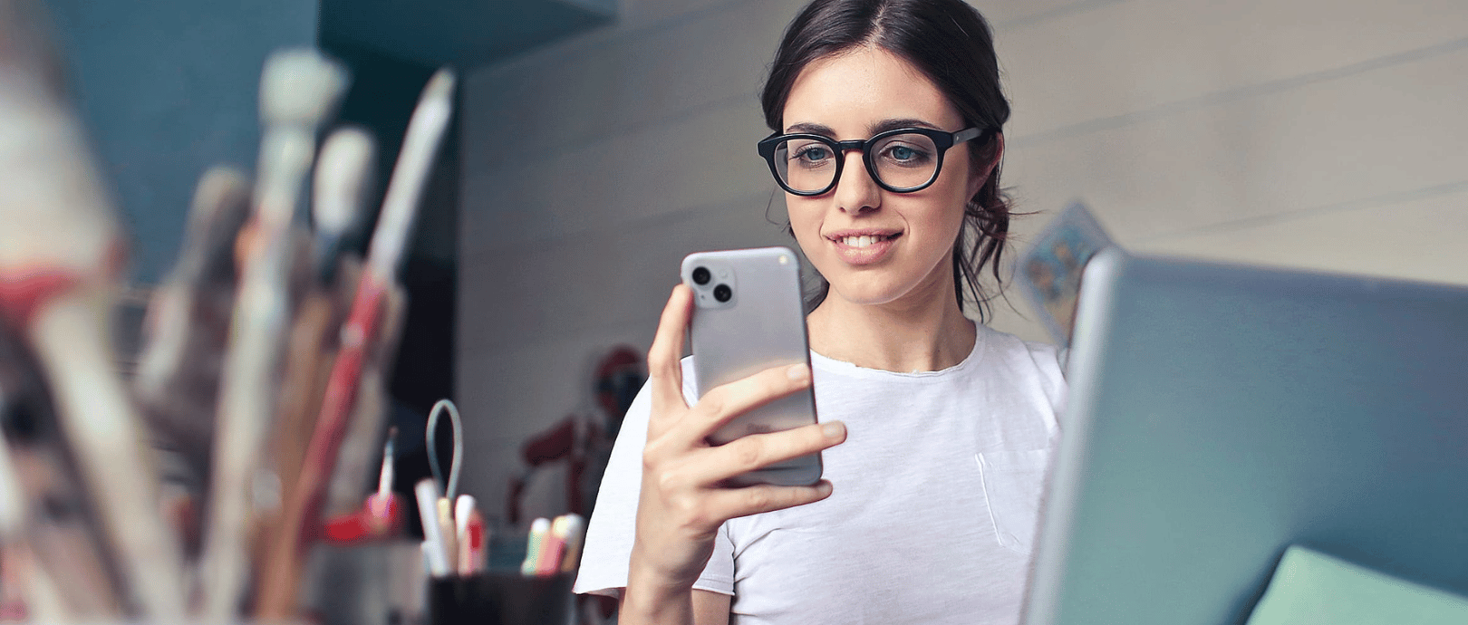 brown haired woman with glasses looking at her mobile device researching the best investment apps