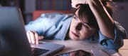 A sleepy woman in front of her laptop.