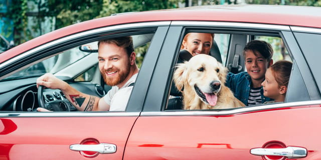 Family in red car with dog
