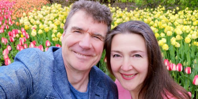 Man and woman smiling in front of tulip garden
