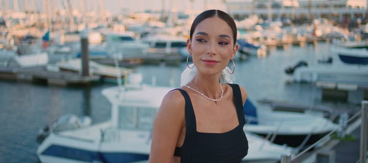 Stylish young woman looking sideways near yachts.
