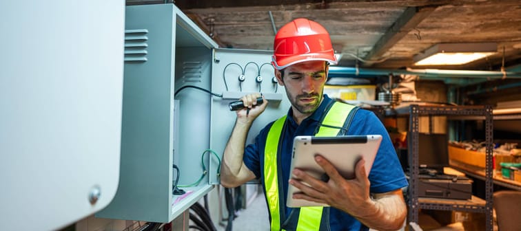 Man working with a tablet and electric box in a basement
