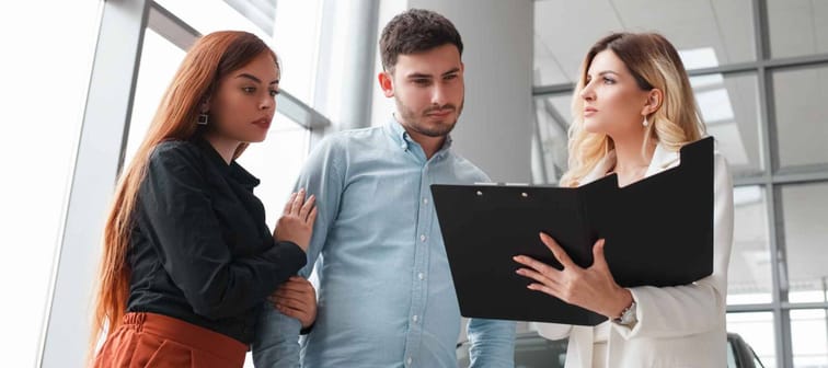Female car saleswoman shows documents to a couple. Buying a car concept