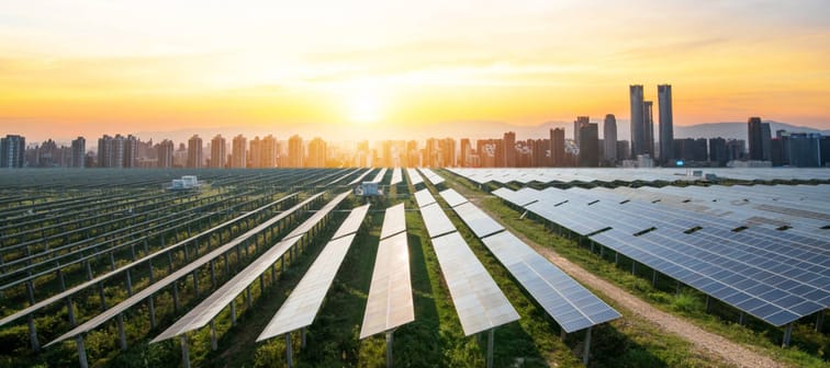 Solar panel field seen in front of city landscape.