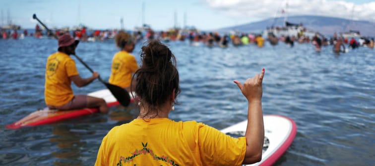 Woman with a surf board in the water with others in the background