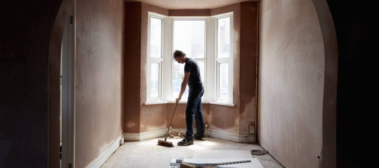A builder sweeps the floor of a renovated home.