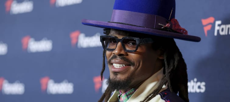 Cam Newton smiling into camera on a red carpet.