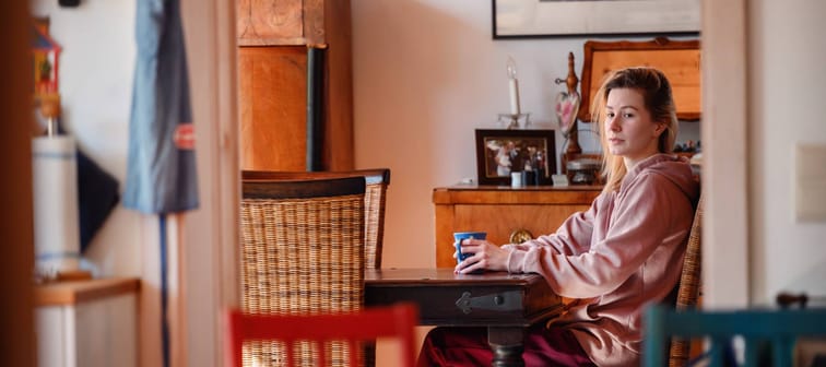 Young woman sitting at table with mug