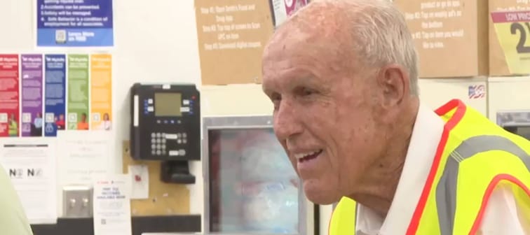 Man in a yellow vest stands at the end of a checkout lane.