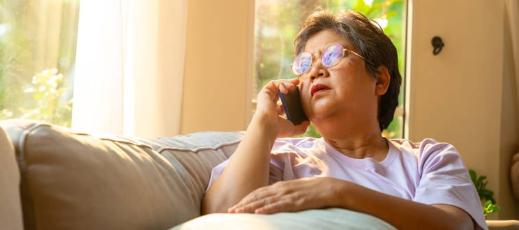 A woman sitting on a couch and talking on the phone.