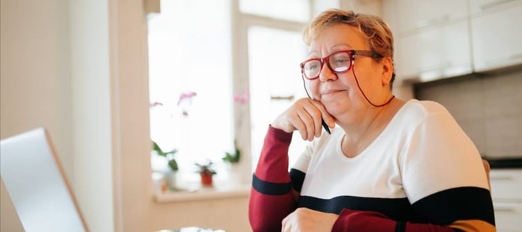 Older woman with glasses looking at her laptop