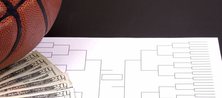 A March Madness tournament bracket with a basketball and fanned money