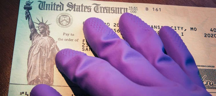 WASHINGTON DC - APRIL 5. 2020: United States Treasury check being held by rubber glove illustrates US Government coronavirus economic impact payment sent to US taxpayers for relief.
