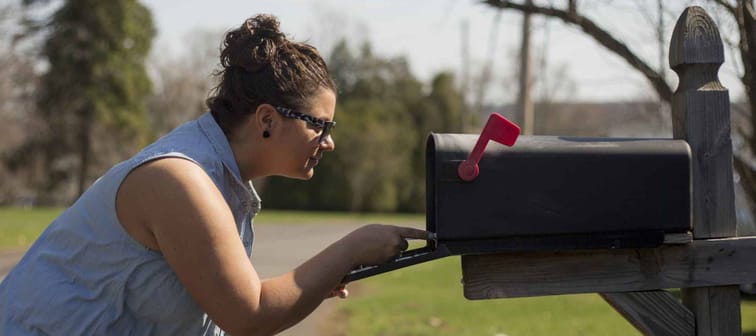 Attractive woman looks inside a mailbox.