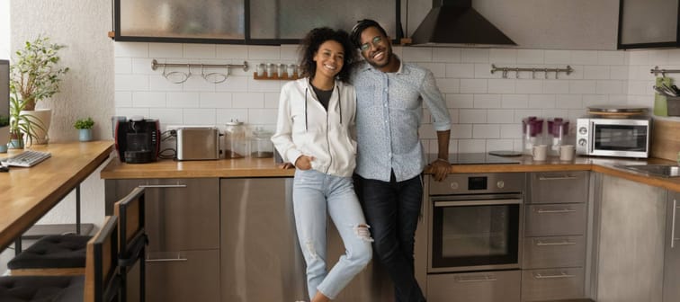 Happy African American couple standing in modern kitchen at home,