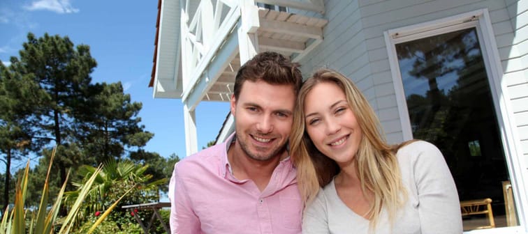 Portrait of smiling couple standing in front of house