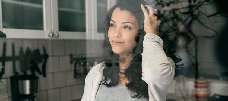 Young Hispanic woman holding coffee cup and looking out a window