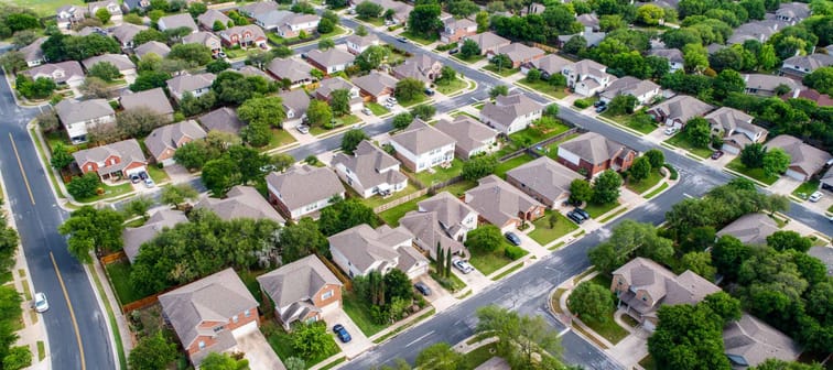 A green neighborhood Suburb houses and homes in new real estate development in Austin , Texas , USA aerial drone view at the corner of the streets